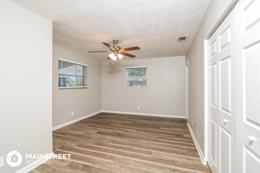 the living room is spacious and has a ceiling fan