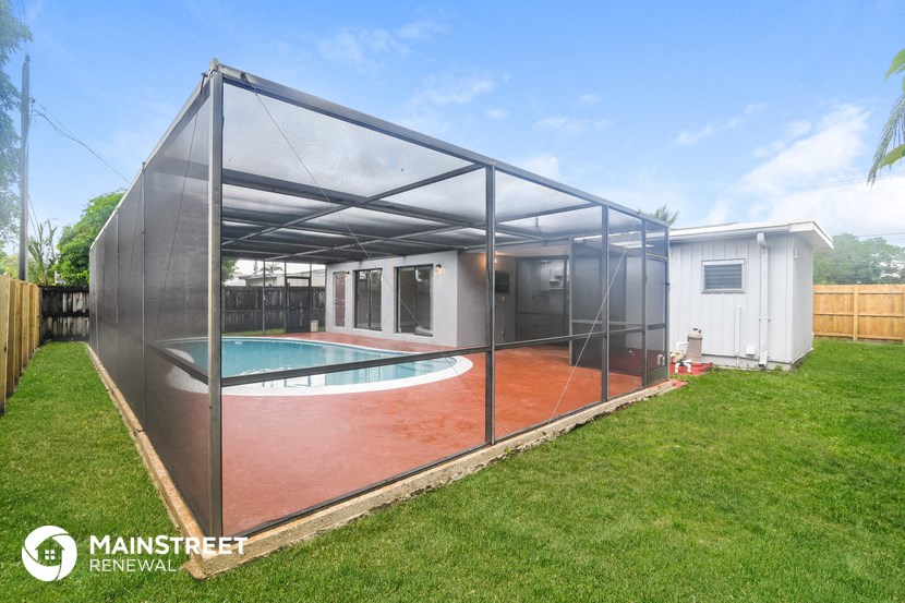 a glassed in pool enclosure with a pool in a backyard