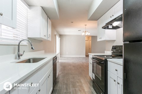 a kitchen with white cabinets and black appliances and a white counter top