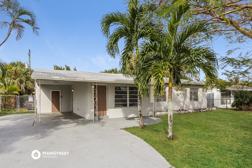 a house with a driveway and palm trees in front of it