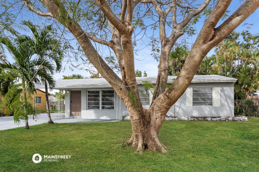 a small white house with a tree in front of it