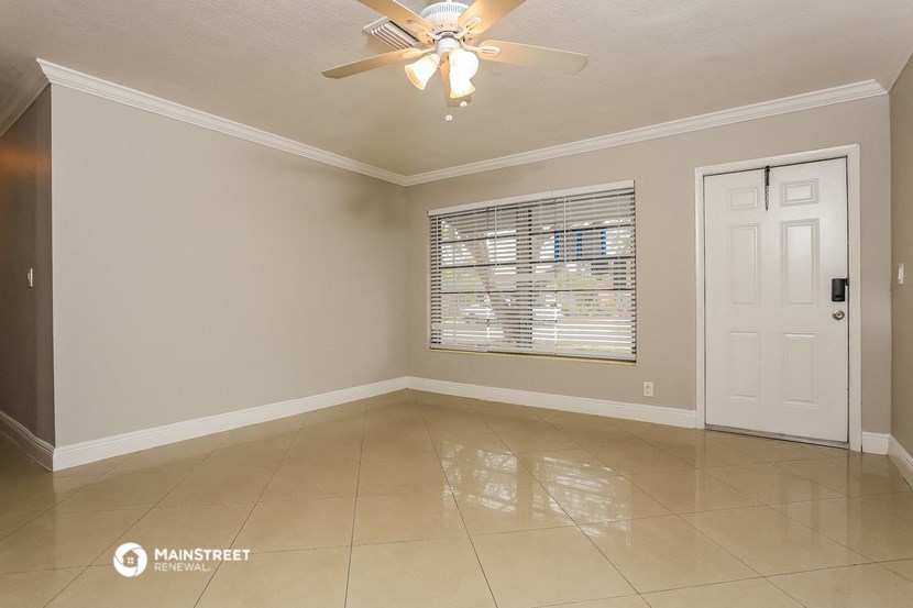 an empty living room with a window and a ceiling fan