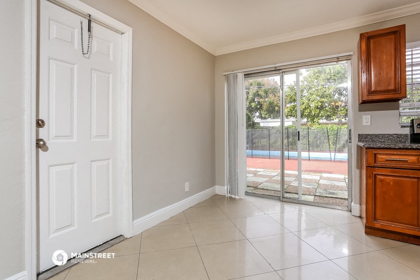 a living room with a door to a balcony and a kitchen
