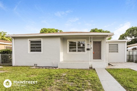 a small white house with a sidewalk and grass