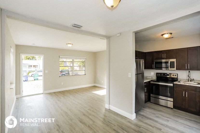 the living room and kitchen of an apartment with wooden floors and stainless steel appliances