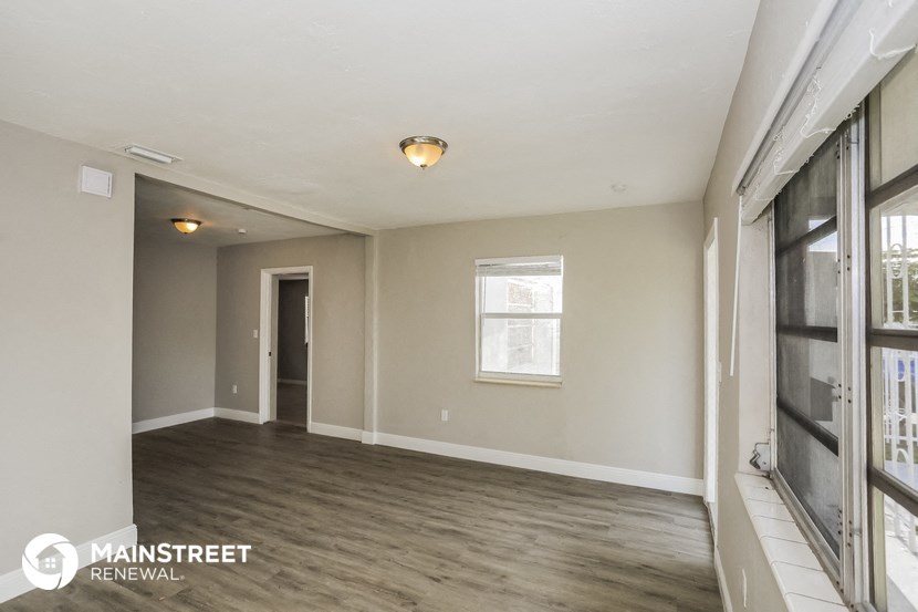 an empty living room with wood floors and a window