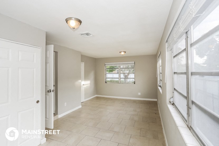 a hallway with a window and a white door and a tiled floor