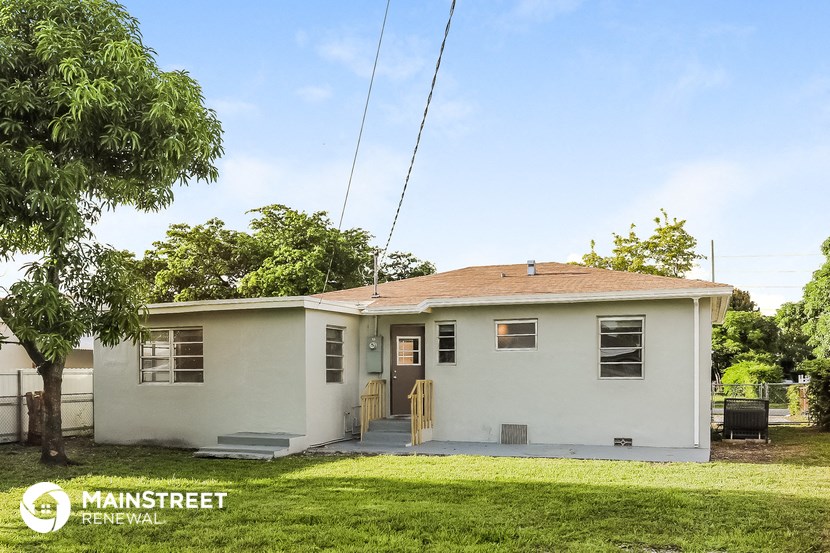 a small white house with a yard and a tree