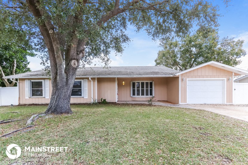 a beige house with a large tree in the yard