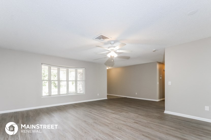 an empty living room with a ceiling fan and a window