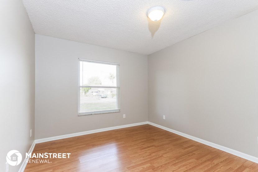 the living room of a house with a wooden floor and a window