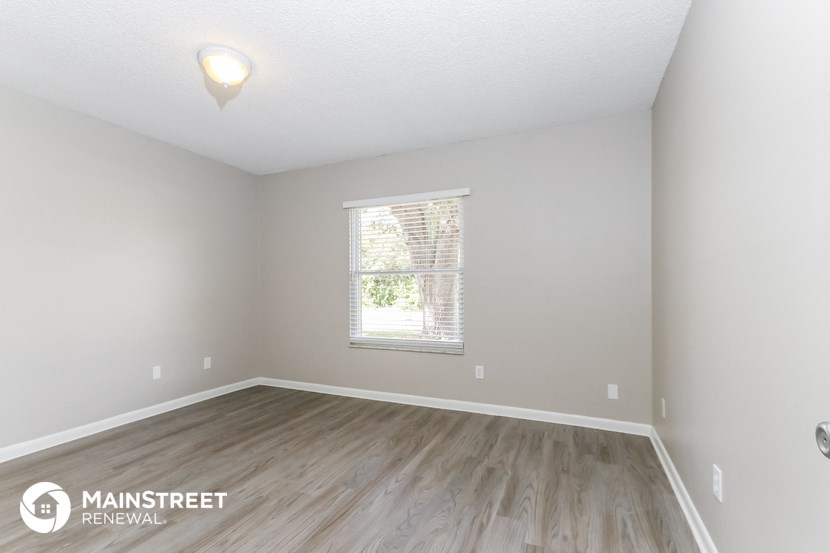 the spacious living room with wood flooring and a window