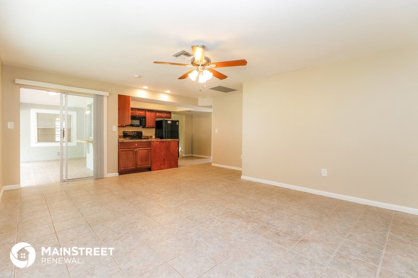 a spacious living room with tile flooring and a ceiling fan