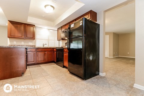 a kitchen with a black refrigerator and wooden cabinets