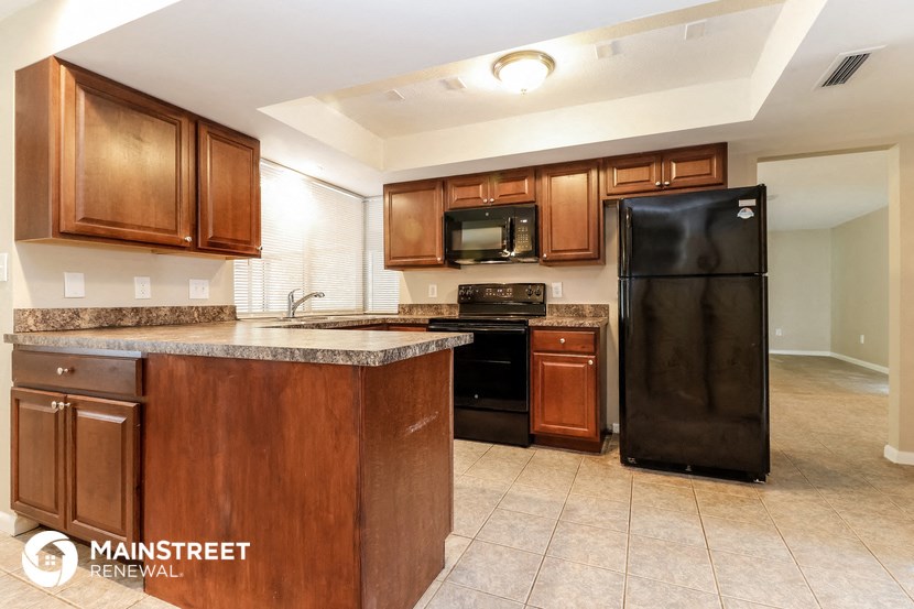 a kitchen with wooden cabinets and a black refrigerator