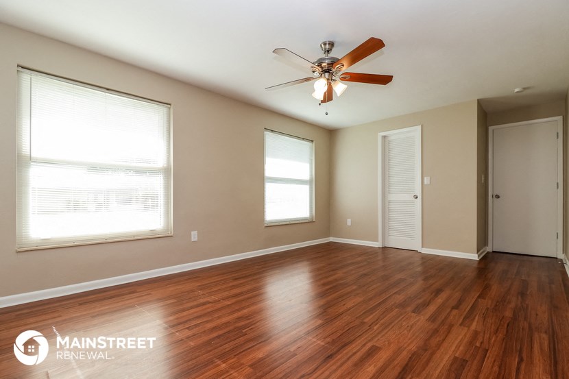 an empty living room with wood floors and a ceiling fan