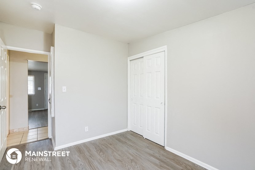 the living room of an apartment with wood flooring and a white door