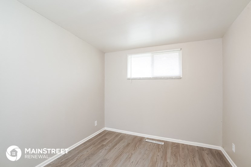 the living room of a home with white walls and a window