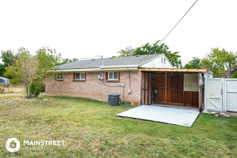 the backyard of a brick house with a garage and a white driveway