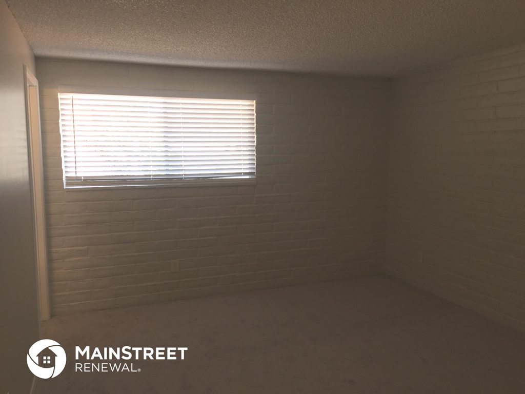 a small room with a window and a white brick wall