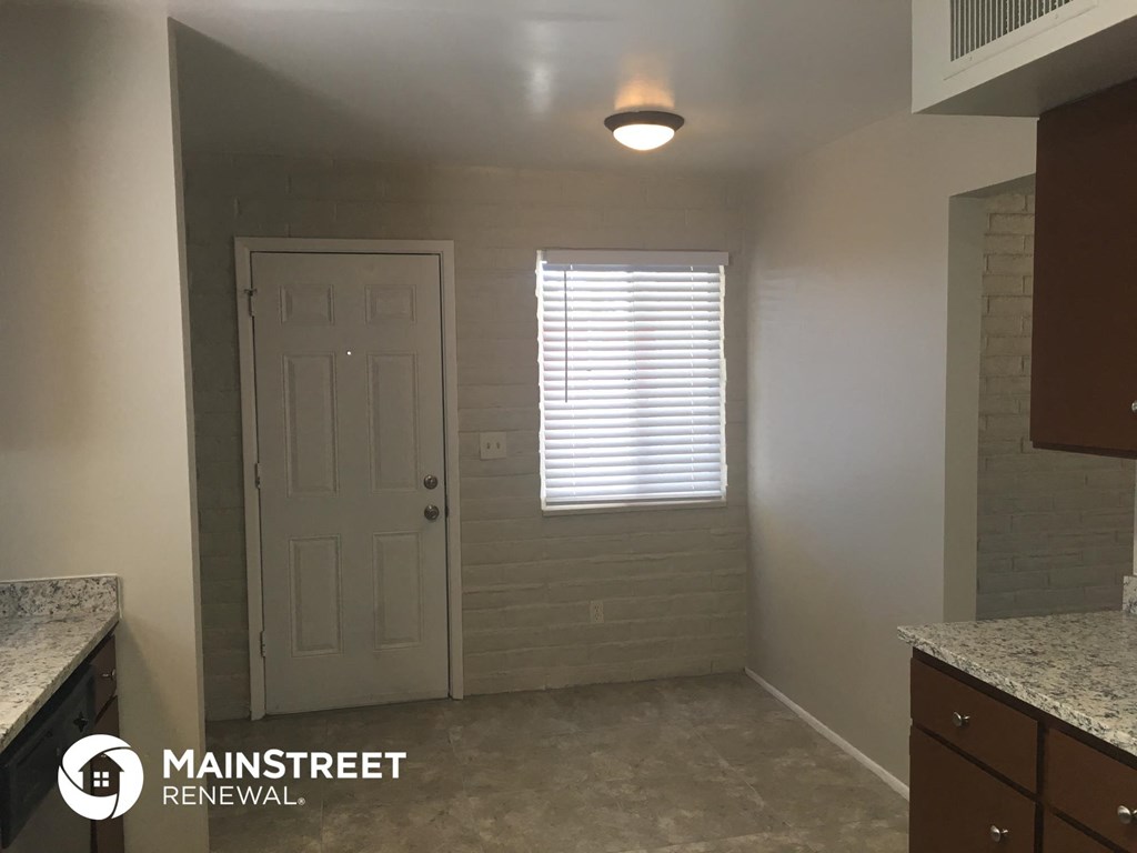 a small kitchen with a white door and a window