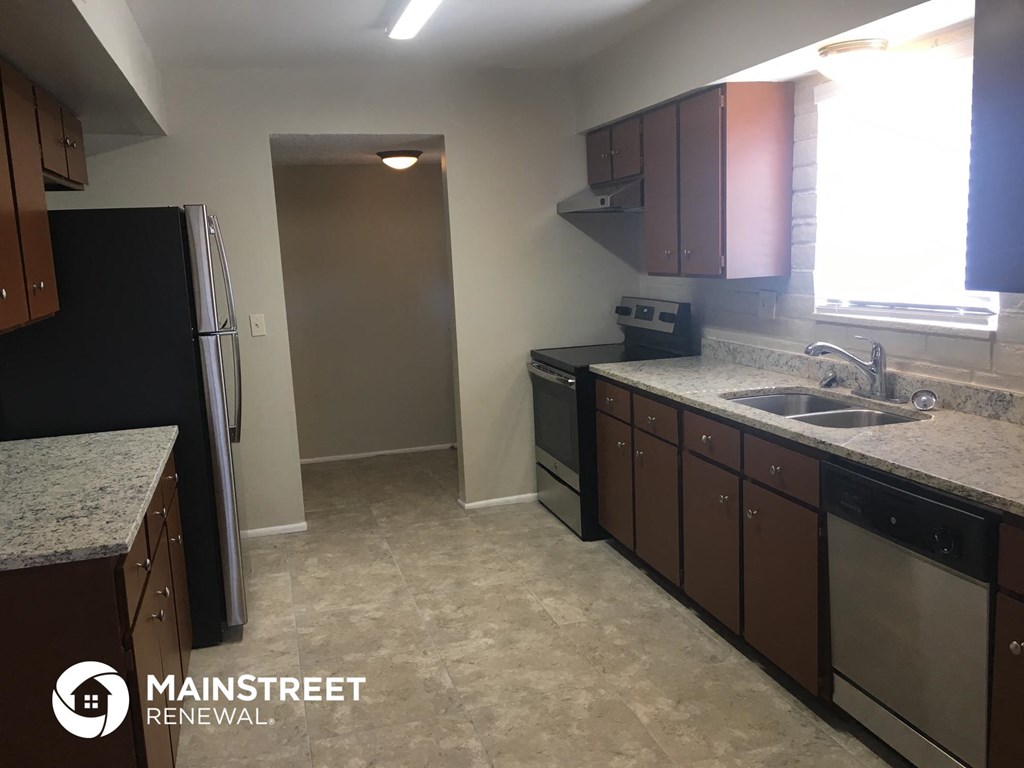 an empty kitchen with a sink and a refrigerator