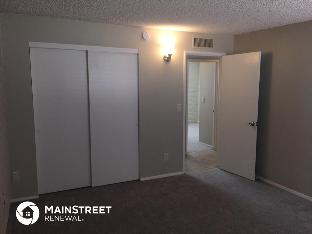 a bedroom with three closets and a carpeted floor and a door to a