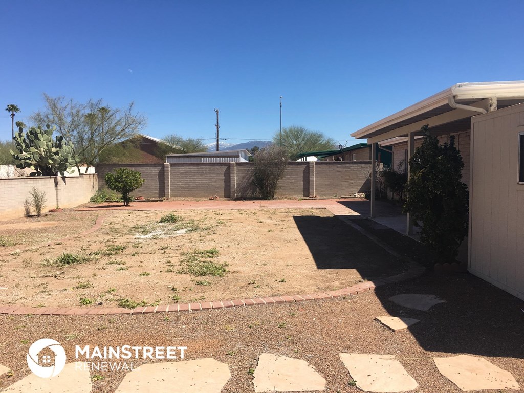 a yard with dirt and a fence and a house