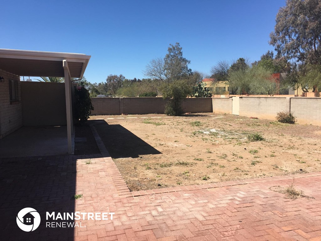 a backyard with a brick patio and a fence
