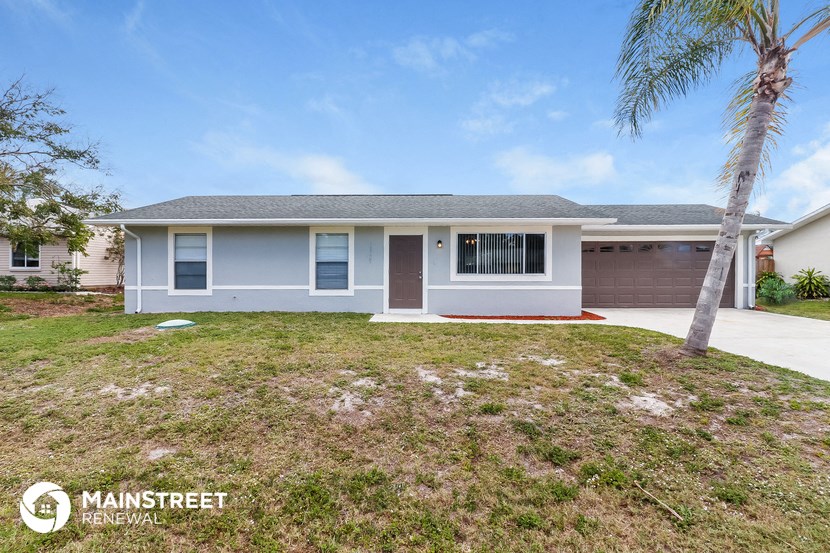 a blue house with a yard and palm tree