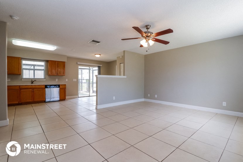 an empty living room and kitchen with a ceiling fan