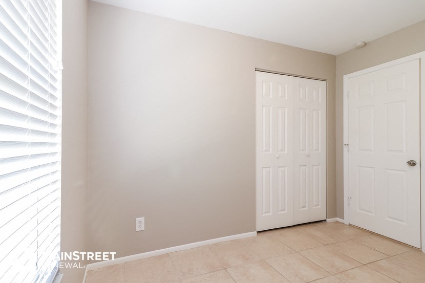 an empty room with two white doors and a tiled floor