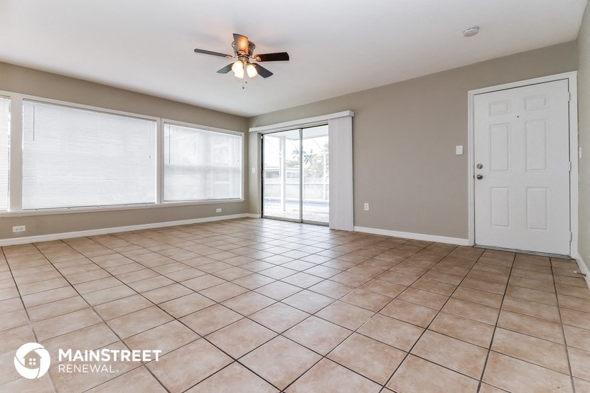 an empty living room with tile flooring and a ceiling fan