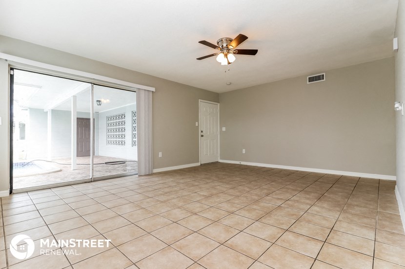 an empty living room with a ceiling fan and tile flooring