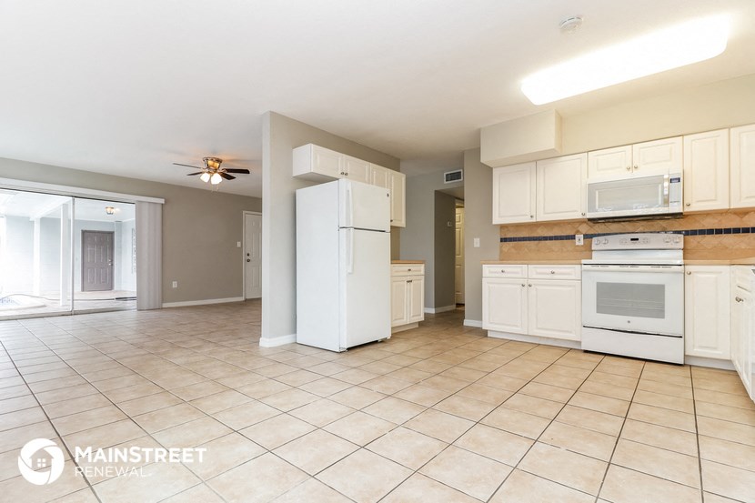a large kitchen with white cabinets and appliances and tiled floors