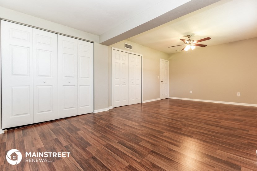the living room of an apartment with wood flooring and a ceiling fan