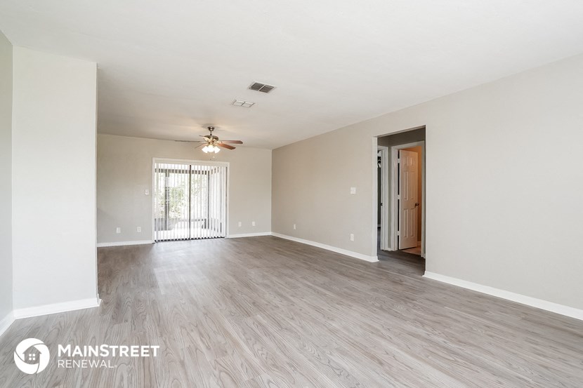 an empty living room with wood flooring and a ceiling fan