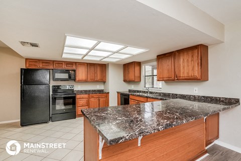 a kitchen with black appliances and granite counter tops and wooden cabinets