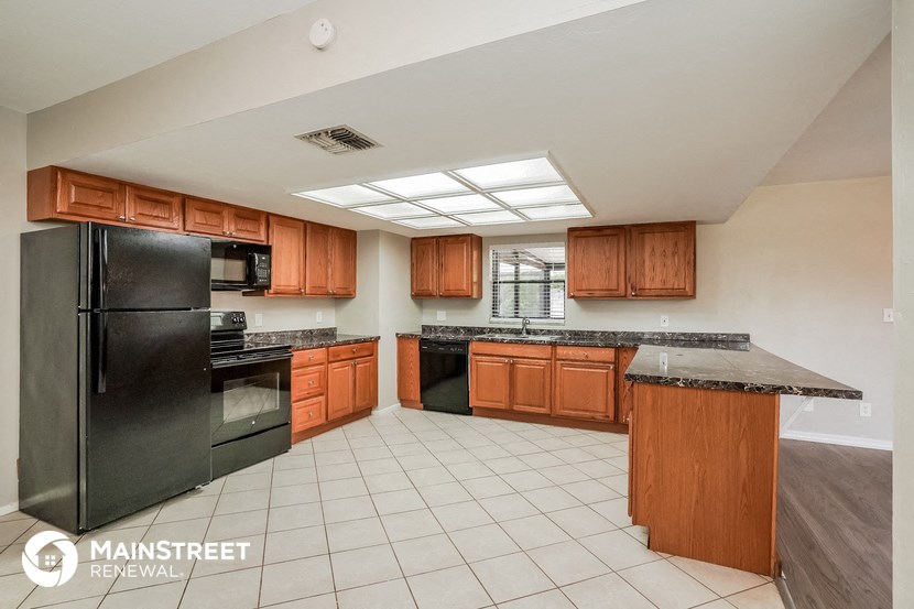 a large kitchen with black appliances and wooden cabinets