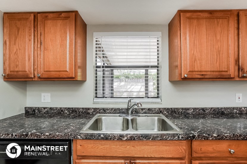 a kitchen with a sink and wooden cabinets and a window