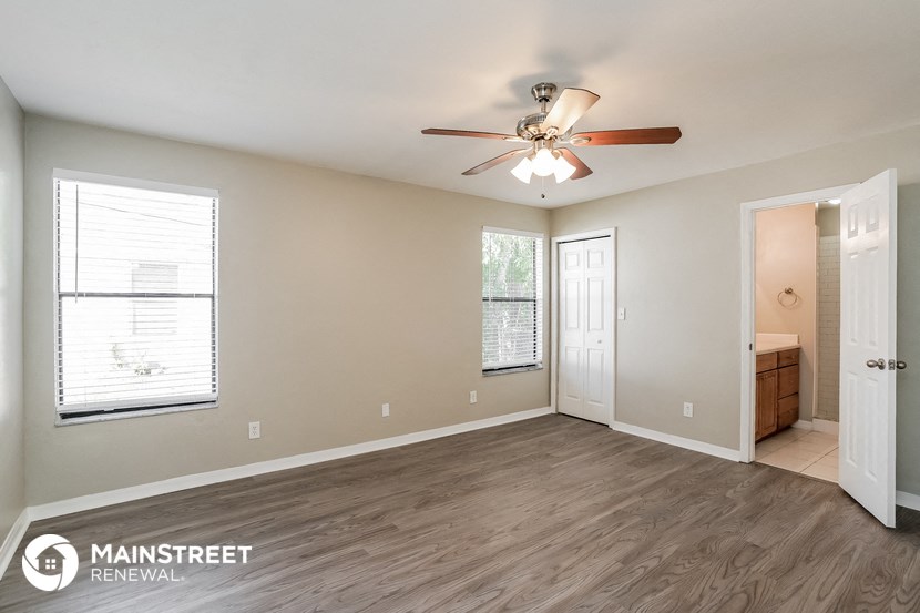 the spacious living room with ceiling fan and wood flooring