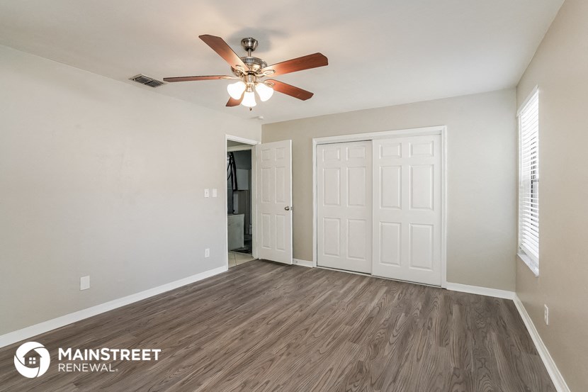 the spacious living room with ceiling fan and wood flooring