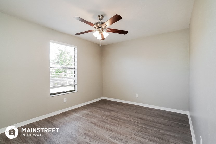 the spacious living room with ceiling fan and wood flooring