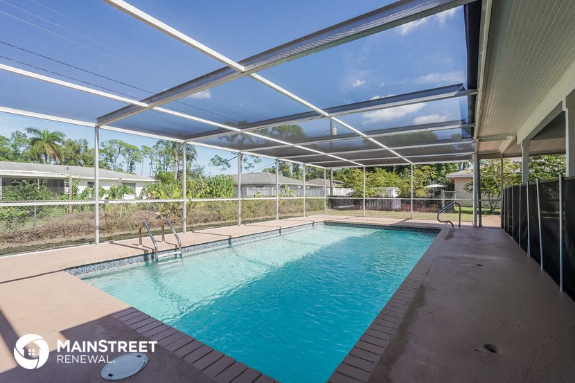 a swimming pool is under a glassed in porch next to a resort style pool