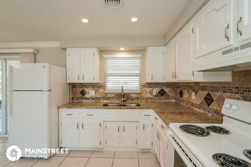 a white kitchen with white appliances and granite counter tops
