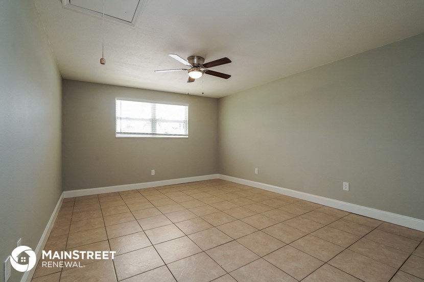 an empty living room with a ceiling fan and a window