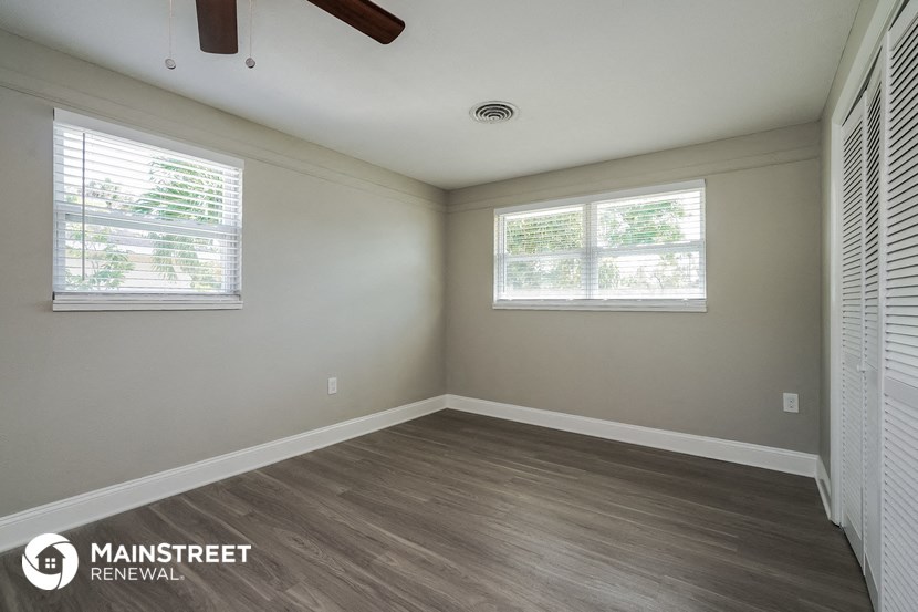 the interior of an empty room with wood flooring and two windows