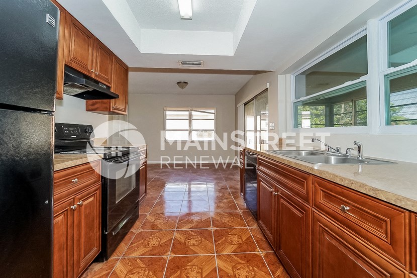 a kitchen with wooden cabinets and black appliances and a large window