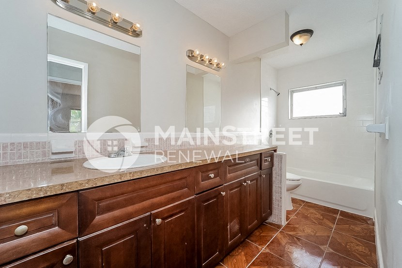 a bathroom with wooden cabinets and a large sink and a toilet