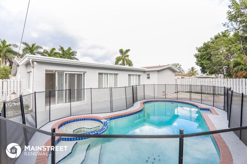a swimming pool with a fence around it and a house in the background